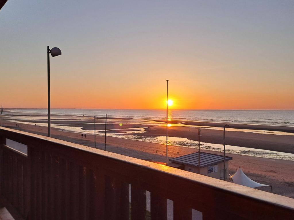 d'un balcon offrant une vue sur la plage au coucher du soleil. dans l'établissement Apartment La Voilerie-3 by Interhome, à Cabourg