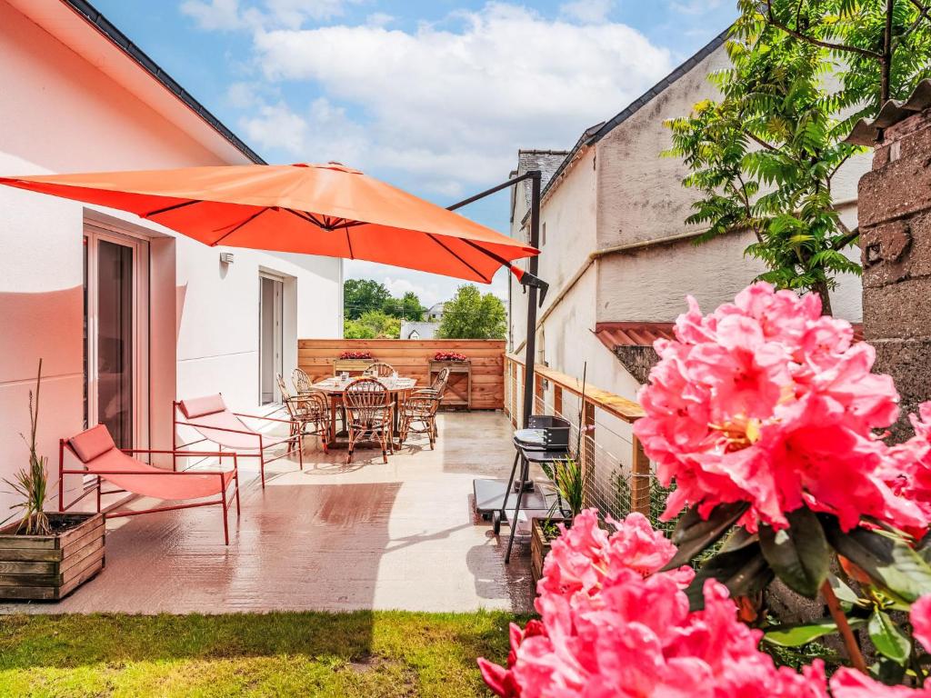 Le BonoにあるHoliday Home Maison Mélusine by Interhomeのテーブルと椅子と傘のあるパティオ