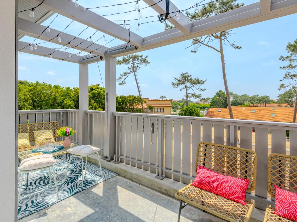 une terrasse avec des chaises, une table et une pergola dans l'établissement Apartment Domaine du belvédère-2 by Interhome, à Mimizan