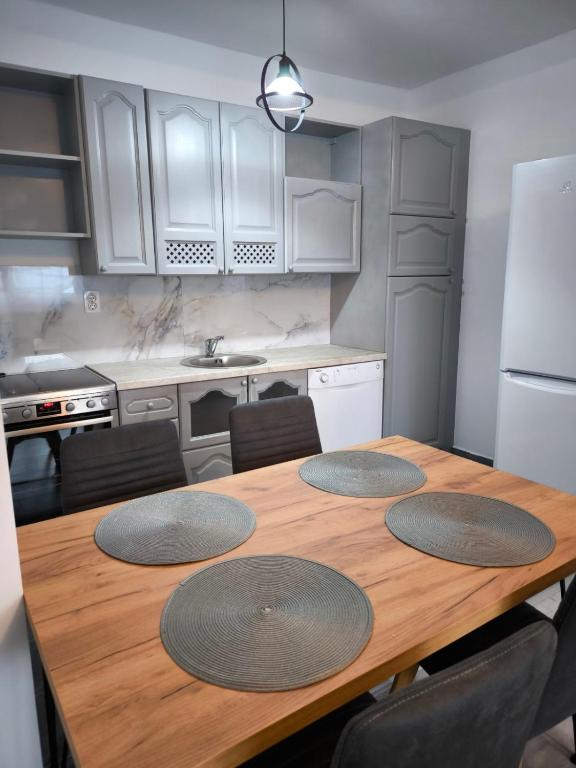 a kitchen with a wooden table with four mats on it at Stan na dan - apartman Lara in Pale