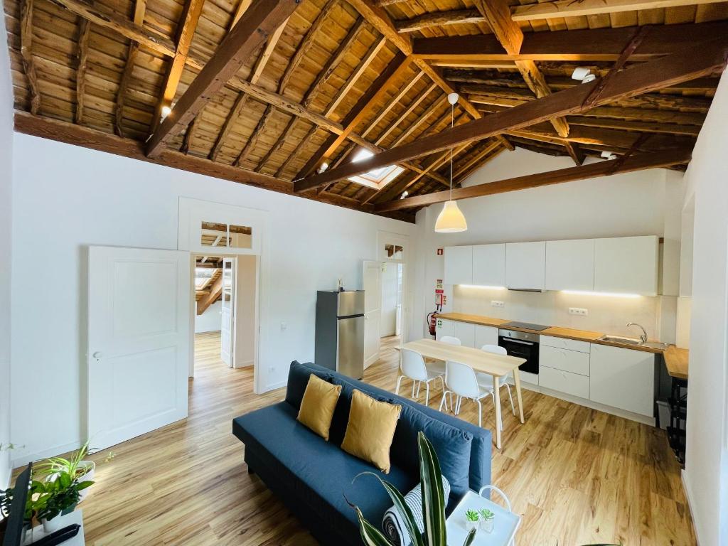 a living room with a blue couch and a kitchen at Casa da Arquitectura - Texturas in Angra do Heroísmo