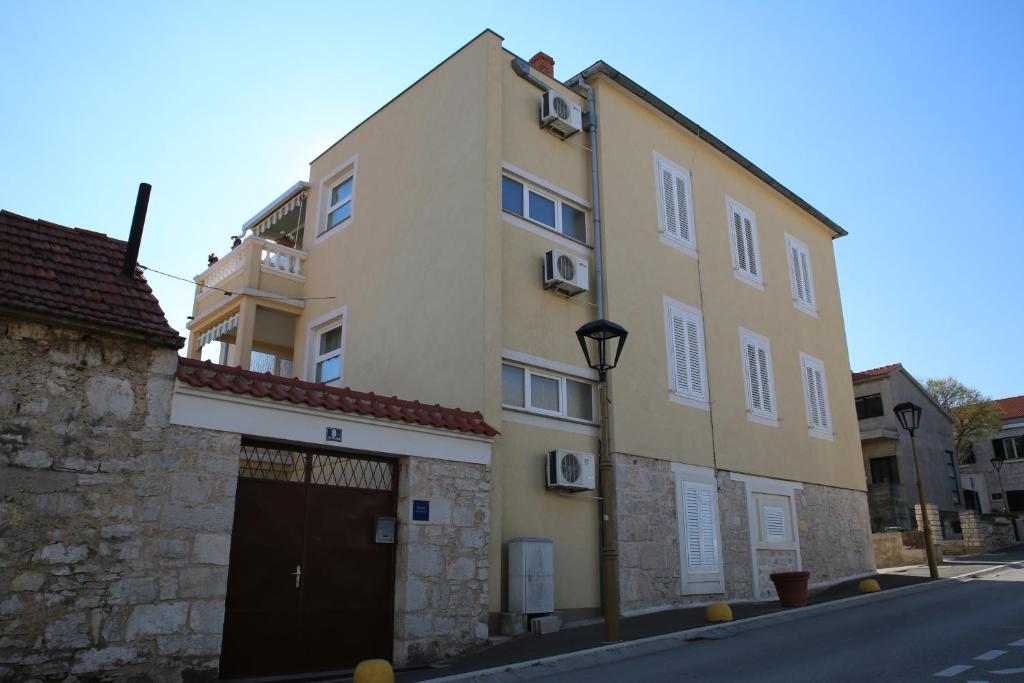 a large yellow building with a garage in a street at Apartments Vila&Zora in Vodice