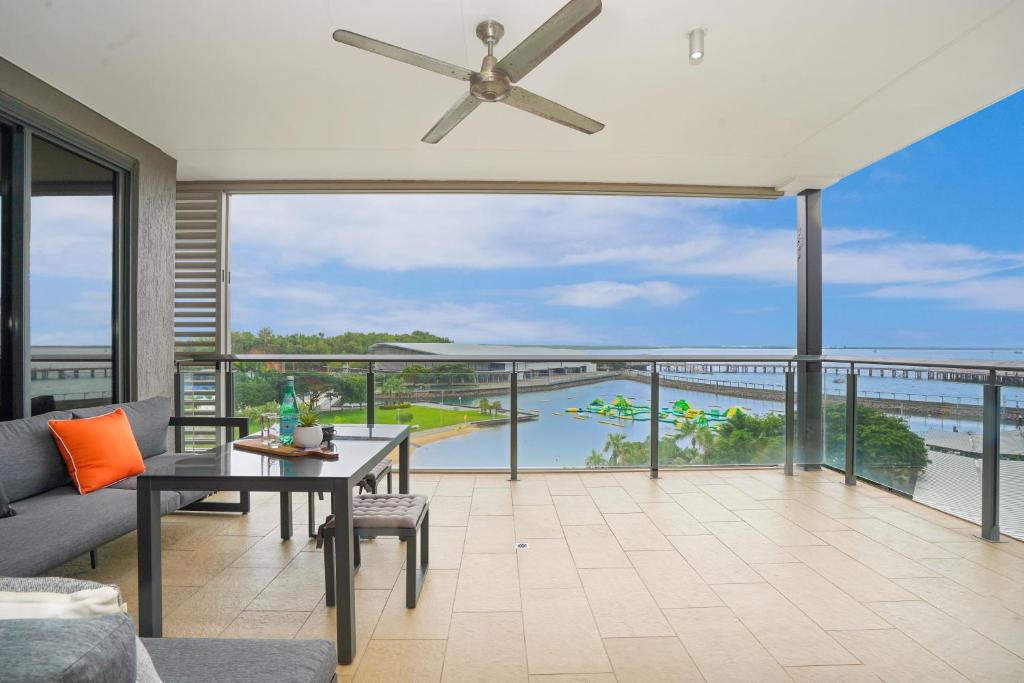a living room with a ceiling fan and a view of the ocean at Picturesque Waterfront Lagoon Views Top Lvl & BBQ in Darwin
