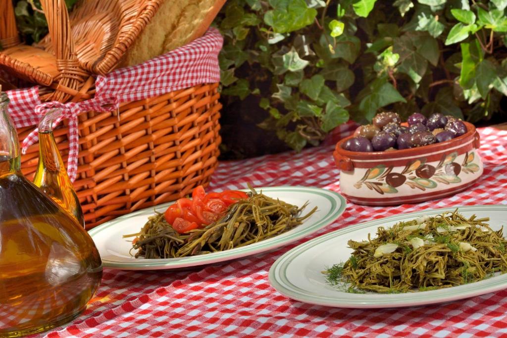 a table with plates of food and a basket of fruit at Gastronomy Hotel Kritsa in Portaria