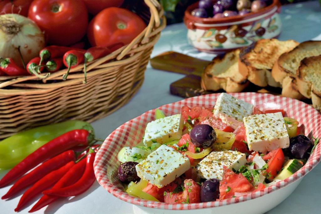 a bowl of food on a table with tomatoes and vegetables at Gastronomy Hotel Kritsa in Portaria