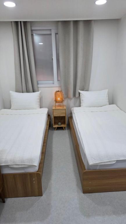 Dos camas individuales en una habitación con ventana. en Alley House 앨리하우스, en Seúl