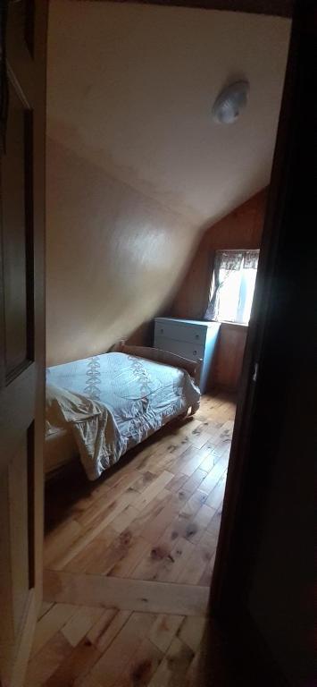 a small bedroom with a bed and a wooden floor at Grangette Entre Chiens et Loups in LʼAnse-Saint-Jean