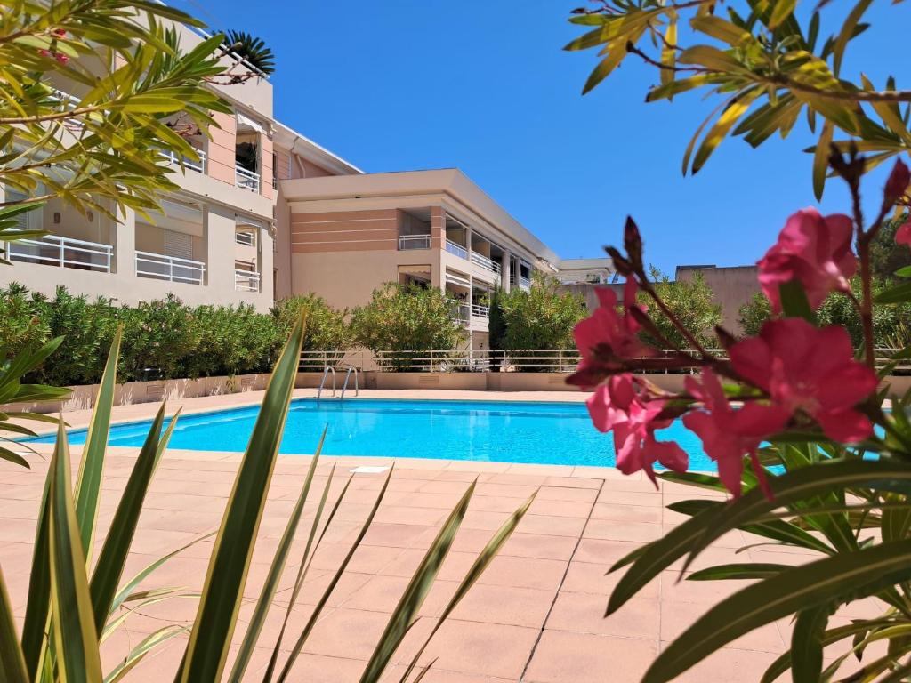 - une piscine en face d'une maison ornée de fleurs roses dans l'établissement Port Azur GOLFE JUAN, à Vallauris