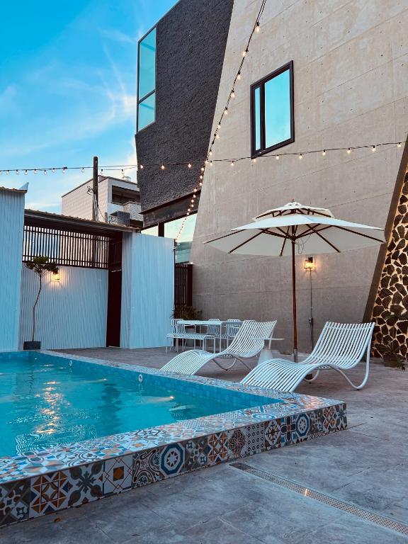 una piscina con due sedie e un ombrellone di 墾丁恆春包棟 l 洛夫特Looft民宿 a Città Vecchia di Hengchun