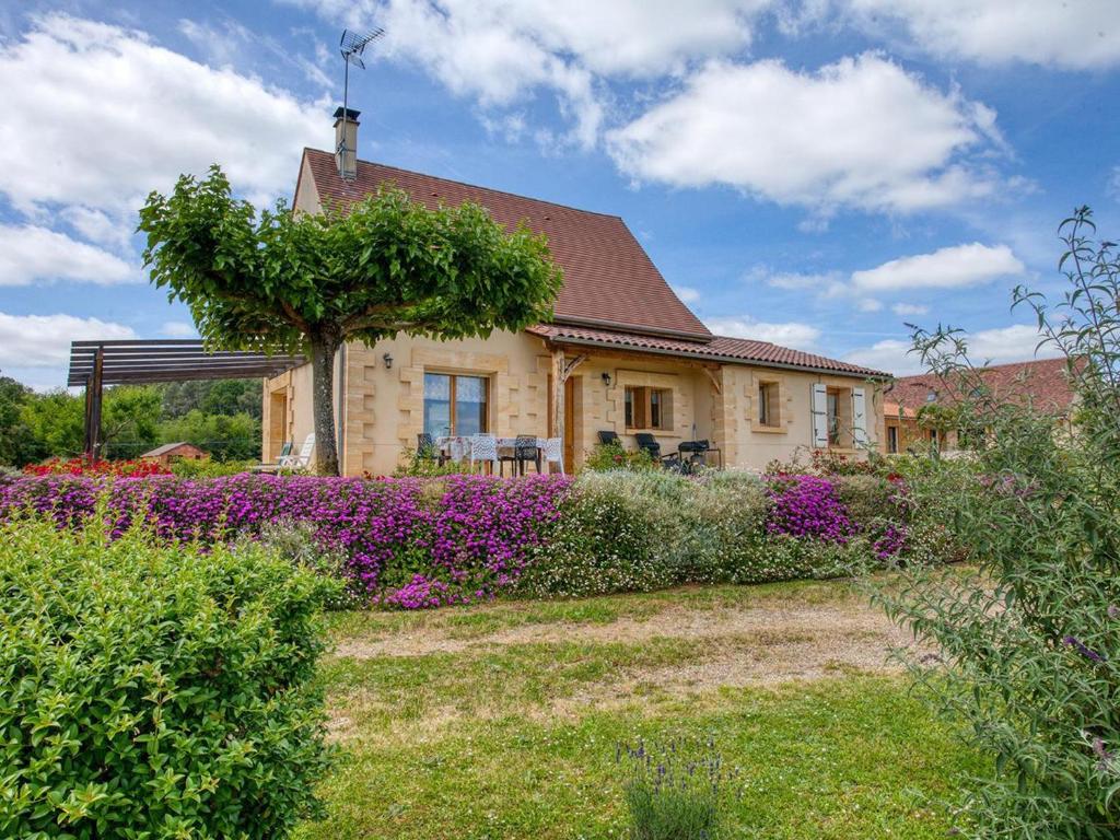 une maison avec des fleurs violettes dans la cour dans l'établissement Maison indépendante avec grand jardin, proche Sarlat, équipée et confortable - FR-1-616-360, à Saint-Vincent-le-Paluel