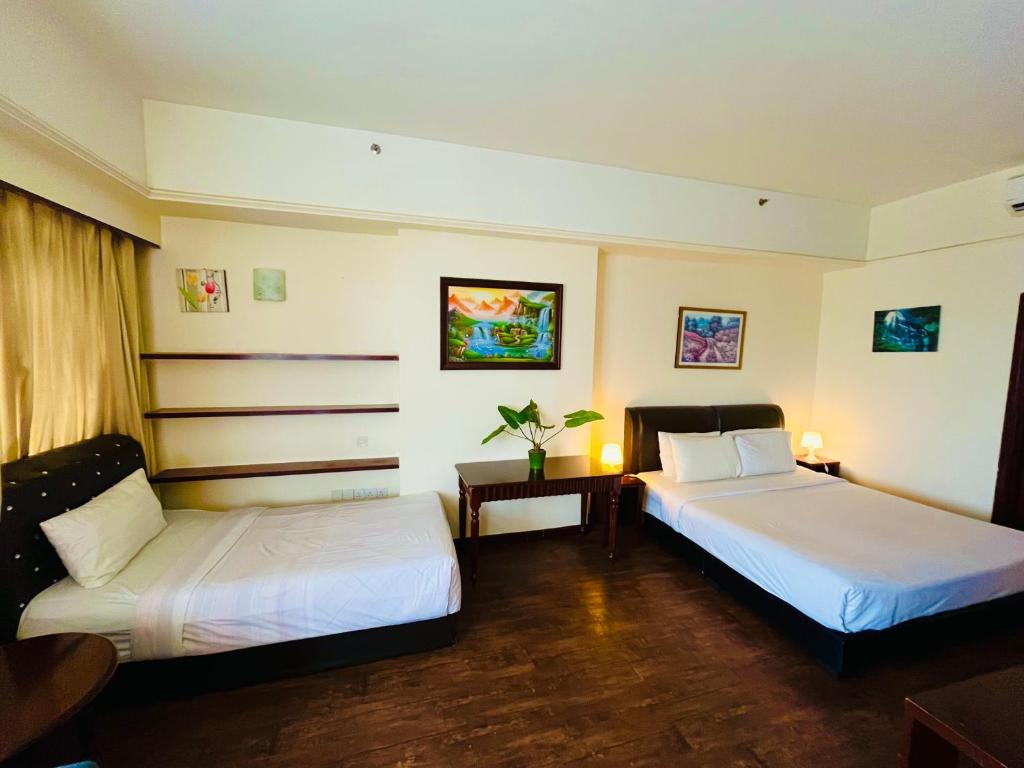 a hotel room with two beds and a table at Max Suites At Barjaya Times Square Kl in Kuala Lumpur