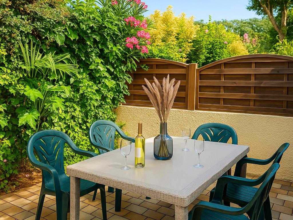 - une table blanche avec des chaises et une bouteille de vin dans l'établissement Pavillon climatisé 2** à 10 min de la plage - 2 chambres, cuisine équipée, parking sécurisé - FR-1-732-47, à Argelès-sur-Mer