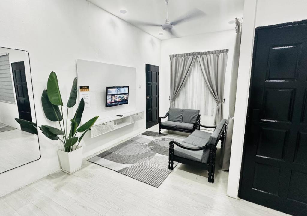 a white living room with a chair and a tv at DVillage Homestay Kelantan Kota Bharu Free Wifi Bilik Aircond in Kota Bharu