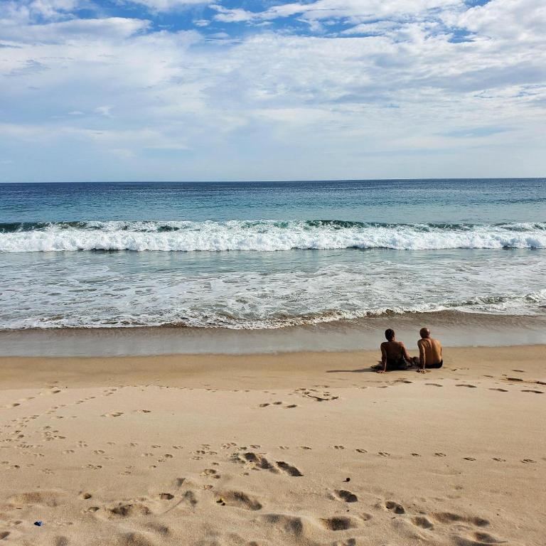 two people sitting on the beach looking at the ocean at Casa Majahualt in San Juan del Sur
