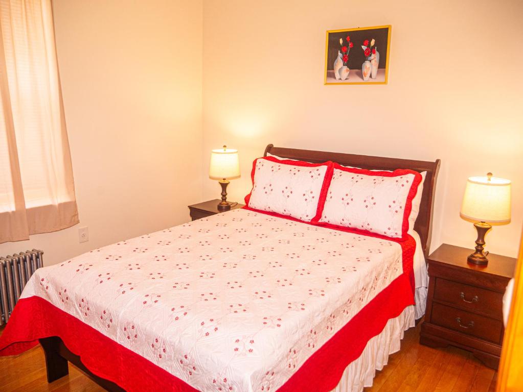 a bedroom with a bed with red and white sheets and two lamps at Immaculate furnished 1-Bedroom Apartment in Sunnyside