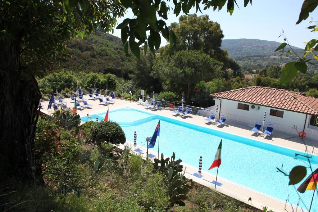 una grande piscina con sedie e una casa di Hotel Villa Giulia a Porto Azzurro