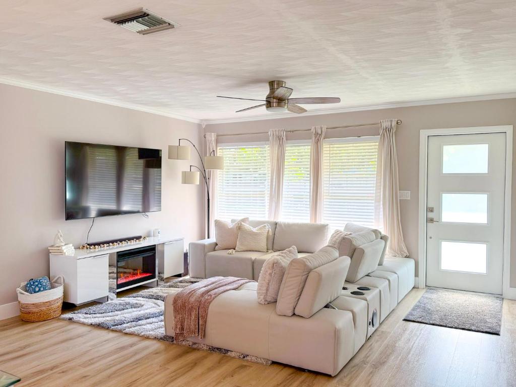 ein Wohnzimmer mit einem weißen Sofa und einem Fernseher in der Unterkunft Rockstar Hideaway Entire Home 2BR 2BA Office Space Guest Room & Outdoor Patio in Hollywood