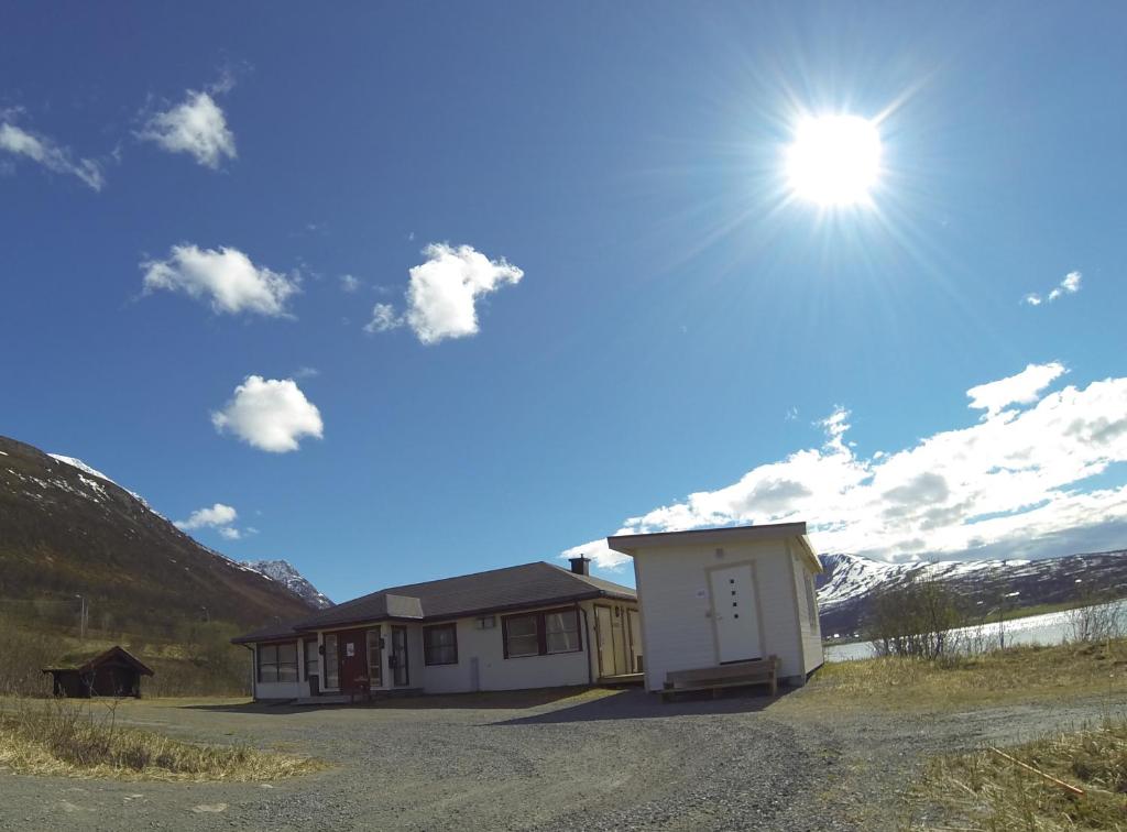 a house on a dirt road with the sun in the sky at Lyngen Fjordcamp in Nord-Lenangen