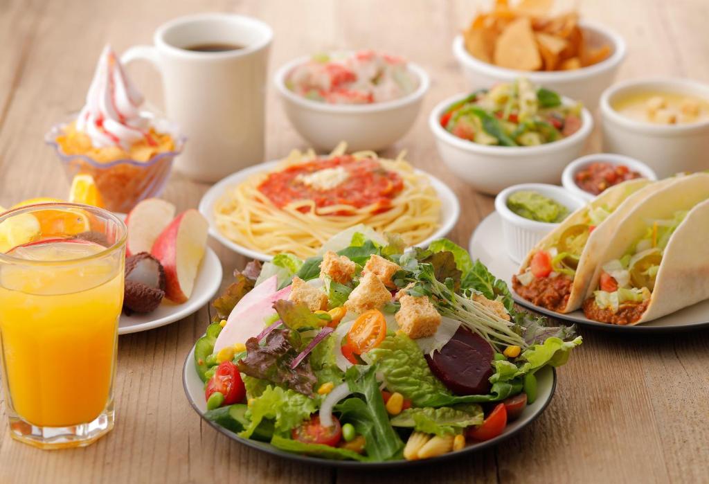 a table with plates of food and a salad and orange juice at Hotel Gracery Shinjuku in Tokyo