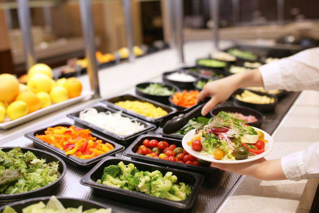 a person holding a plate of food in a buffet at Hotel Gracery Shinjuku in Tokyo