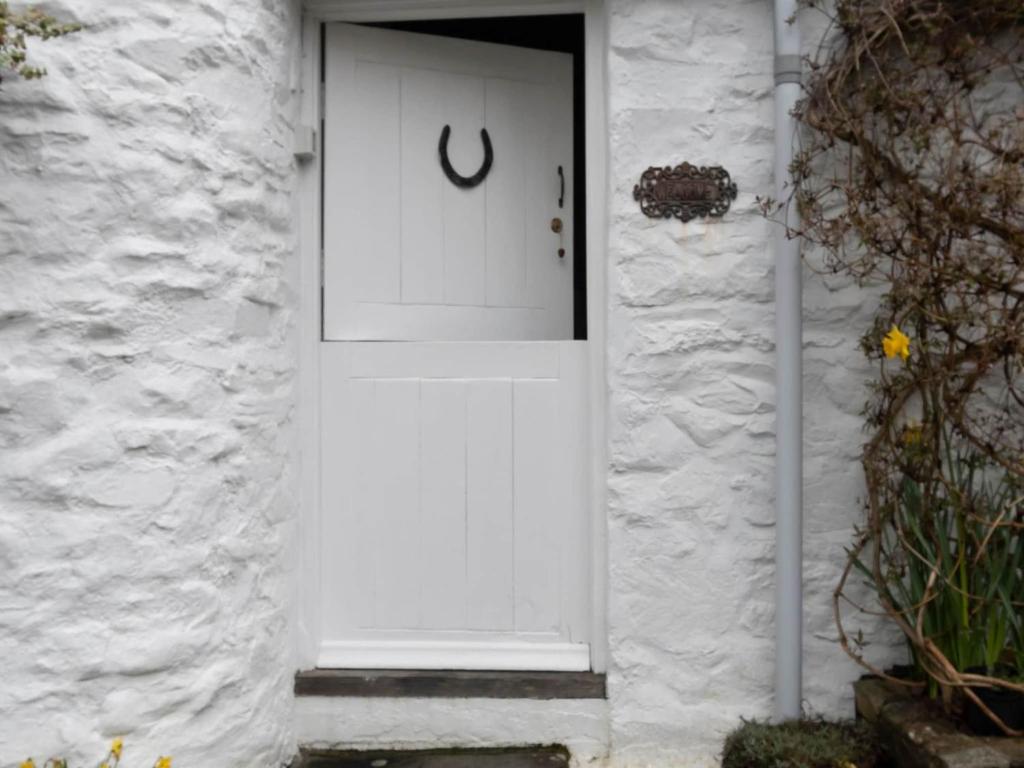 a white door on a white brick house at Secluded Holiday Home in Ceredigion with Garden in Pennant