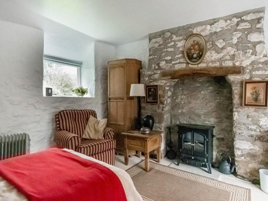 a bedroom with a stone fireplace and a chair at Secluded Holiday Home in Ceredigion with Garden in Pennant