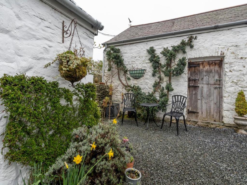 a garden with two chairs and a table next to a building at Secluded Holiday Home in Ceredigion with Garden in Pennant