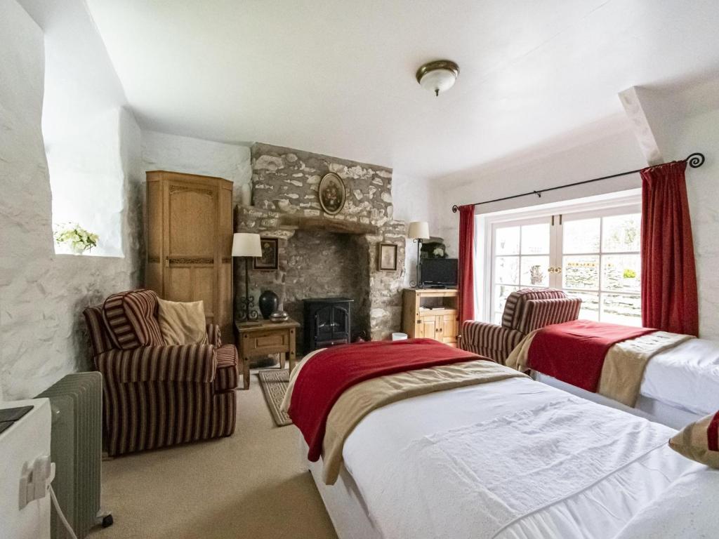 a bedroom with a bed and two chairs and a fireplace at Secluded Holiday Home in Ceredigion with Garden in Pennant