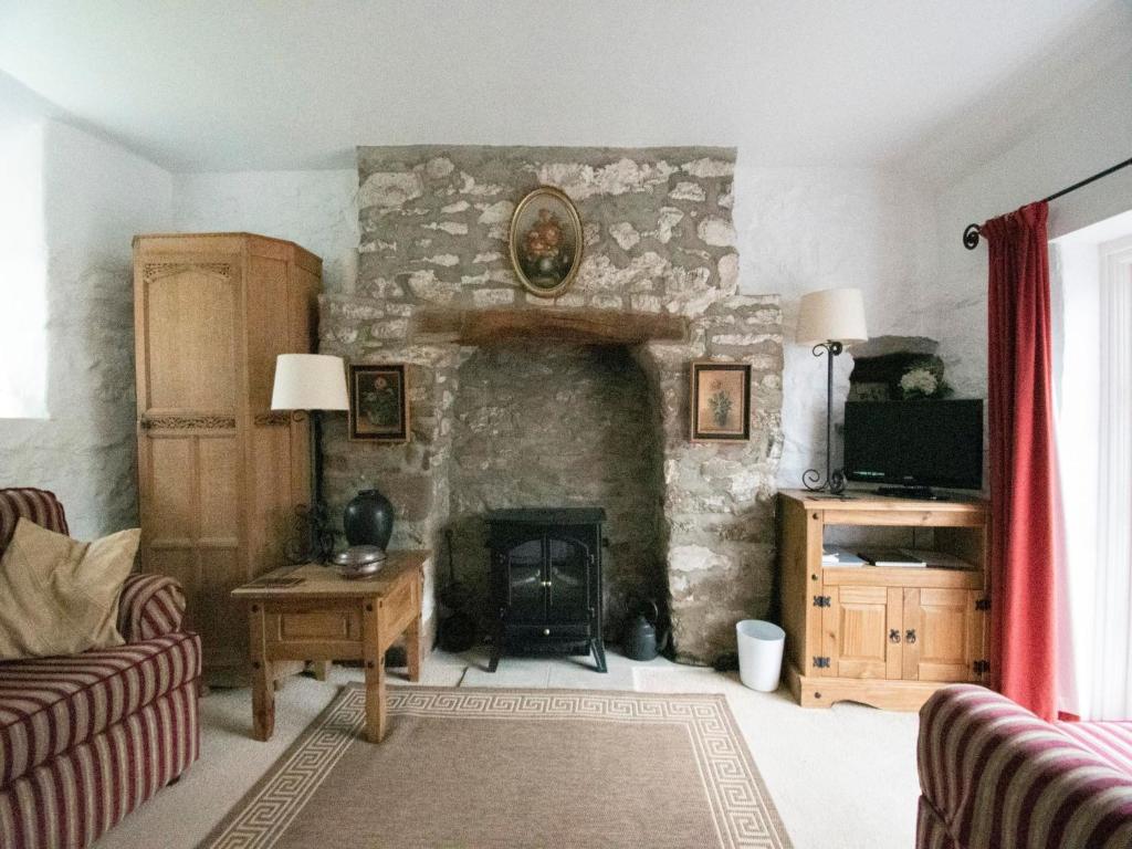 a living room with a stone fireplace with a tv at Secluded Holiday Home in Ceredigion with Garden in Pennant