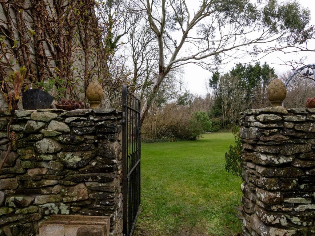a stone fence with a stone wall and a tree at Secluded Holiday Home in Ceredigion with Garden in Pennant