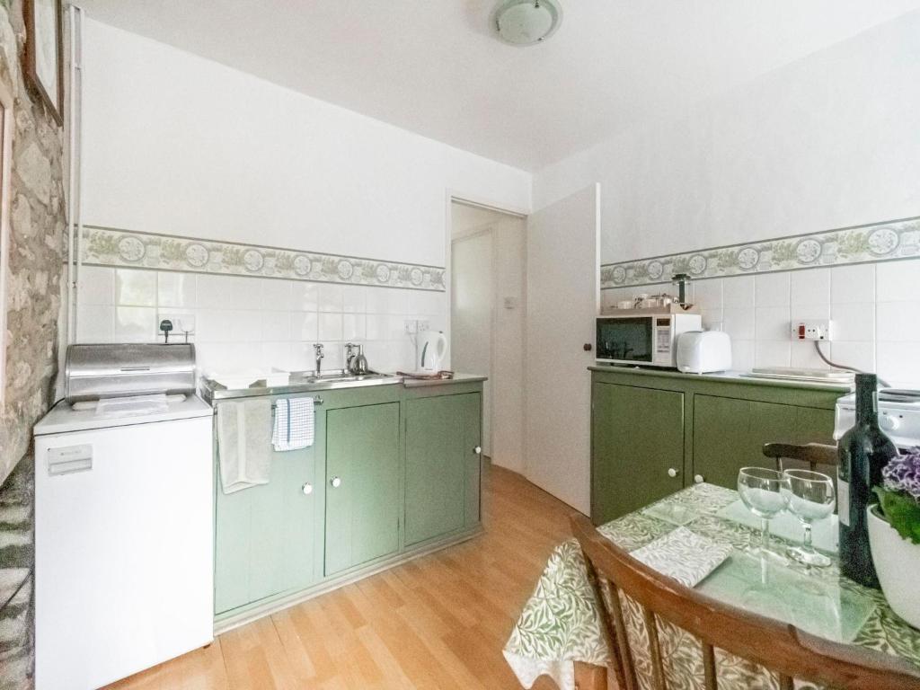 a kitchen with green cabinets and a table at Secluded Holiday Home in Ceredigion with Garden in Pennant