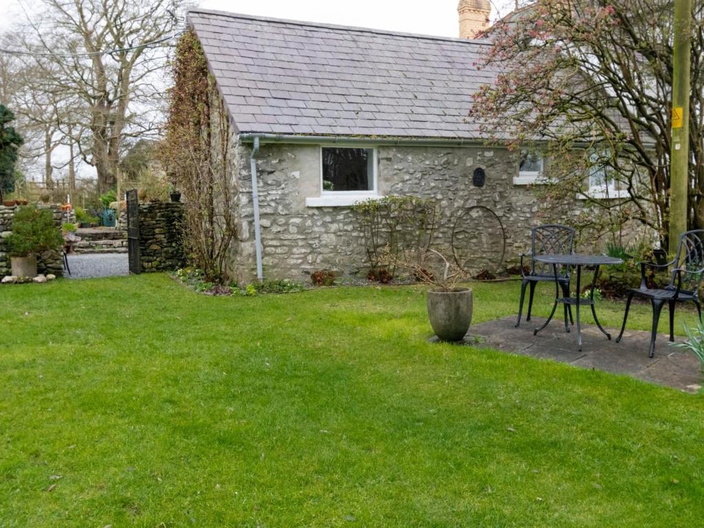 a stone house with a table and chairs in a yard at Secluded Holiday Home in Ceredigion with Garden in Pennant