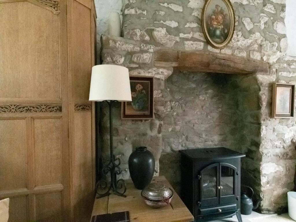 a lamp sitting on a table next to a stone fireplace at Secluded Holiday Home in Ceredigion with Garden in Pennant
