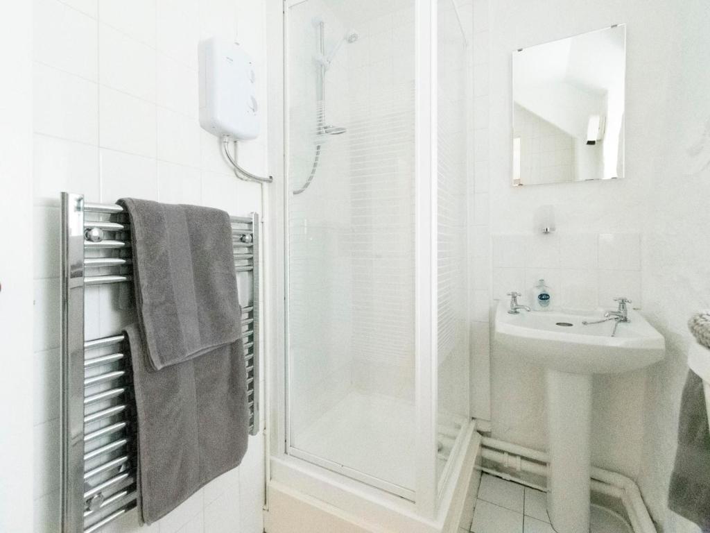 a white bathroom with a shower and a sink at Secluded Holiday Home in Ceredigion with Garden in Pennant