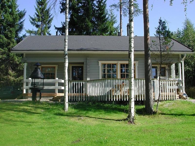 a small house with a white fence in a yard at Ylä-Saarikko Holiday Cottages in Kuusa