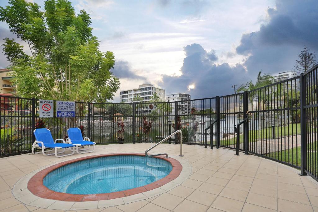 a swimming pool with two chairs and a fence at K Resort Surfers Paradise Apartments in Gold Coast