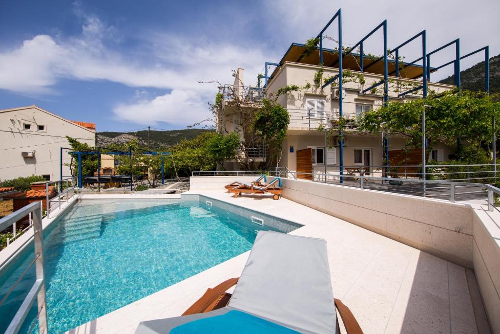 a swimming pool with chairs and a house at Apartments Zambarlin in Komiža