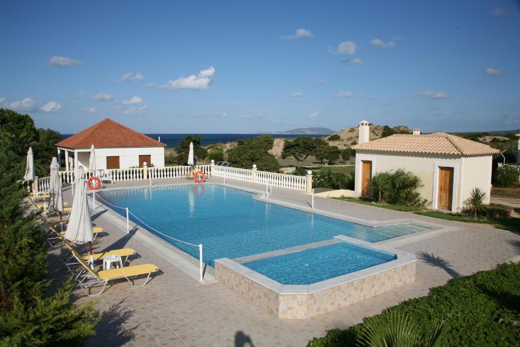 duży basen z krzesłami i dom w obiekcie Navarone Beach Apartments w mieście Petrokhorion