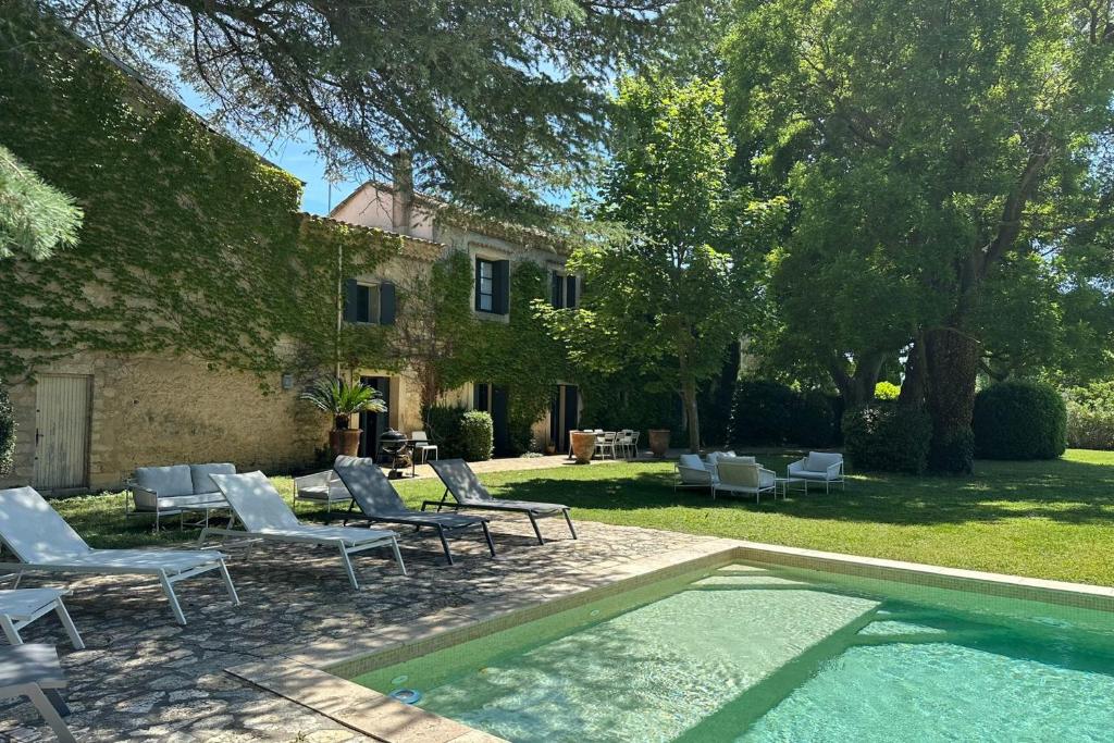 una piscina con sedie a sdraio e una casa di The Grand Mas Domaine du Moulin de Perdrix a Mudaison