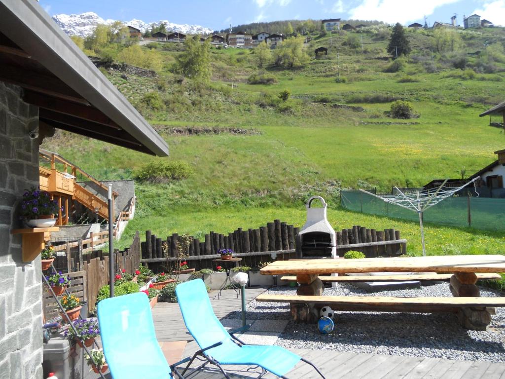 eine Terrasse mit einem Picknicktisch und Stühlen sowie einem Hügel in der Unterkunft Casa Paola in Valfurva