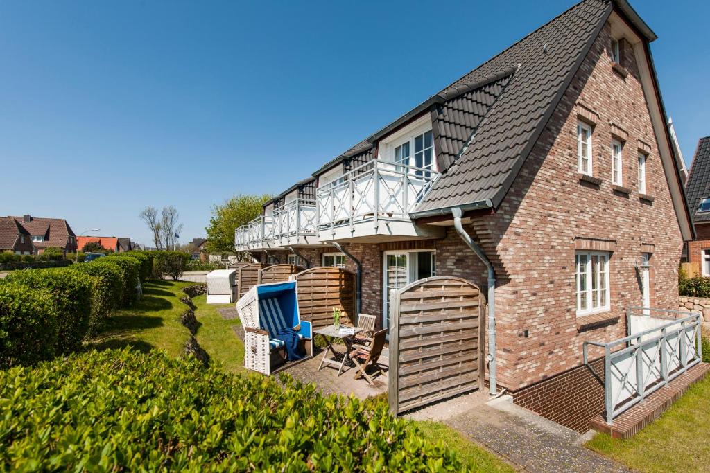 a brick house with a balcony and a patio at Friesenhaus Sylter Domizil in Wenningstedt
