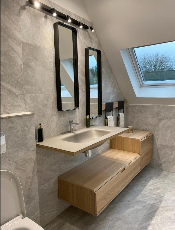 une salle de bain avec un lavabo et deux miroirs dans l'établissement Villa Proche paris, à Servon