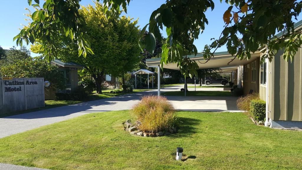 a building with a yard with a bird in the grass at Catlins Area Motel in Owaka