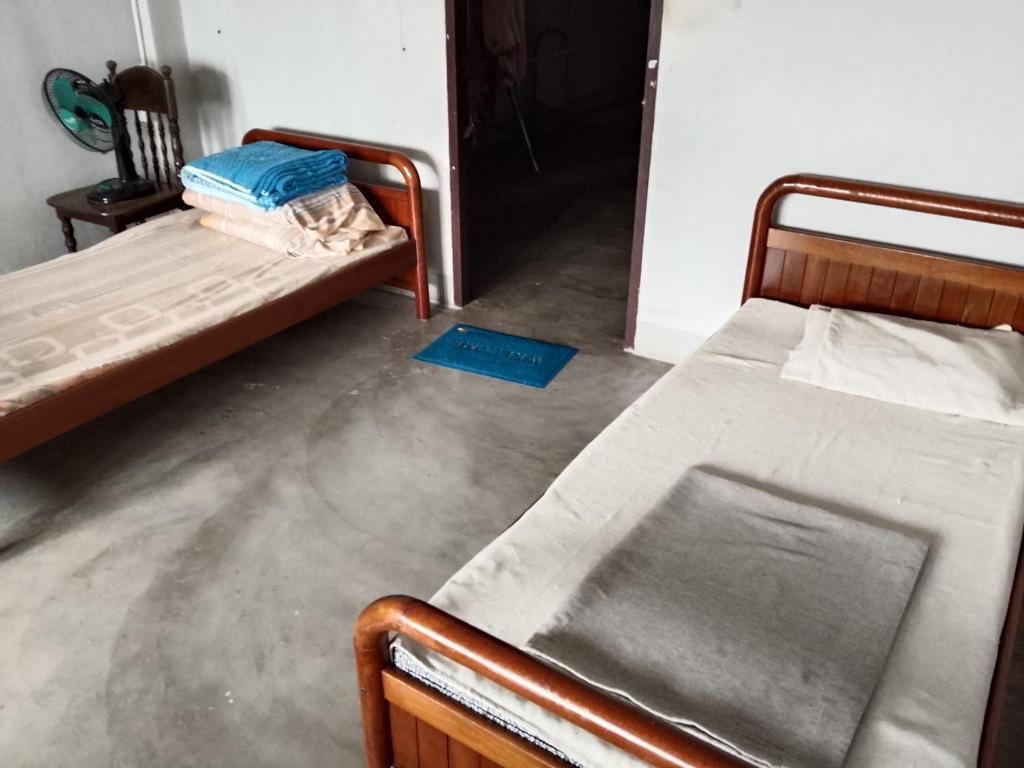 a room with two beds and a blue mat on the floor at Moonshadow in Sungai Kolok