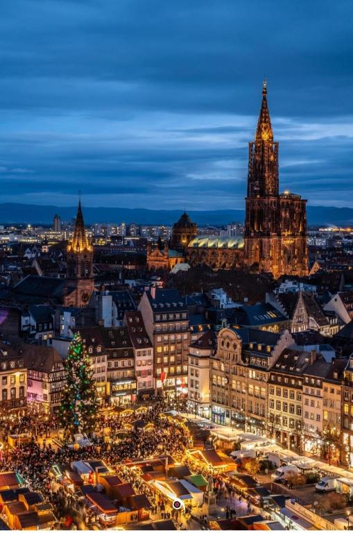 une ville éclairée la nuit avec une tour d'horloge dans l'établissement Logement Moderne, à Mundolsheim