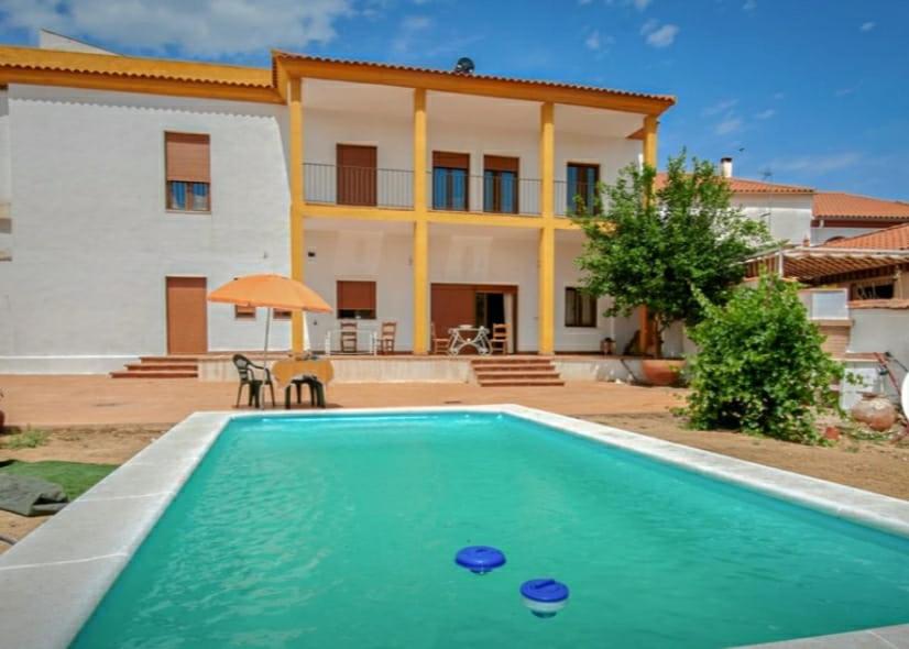 eine Villa mit einem Swimmingpool vor einem Haus in der Unterkunft Vivienda Rural El Retiro in Villanueva del Rey