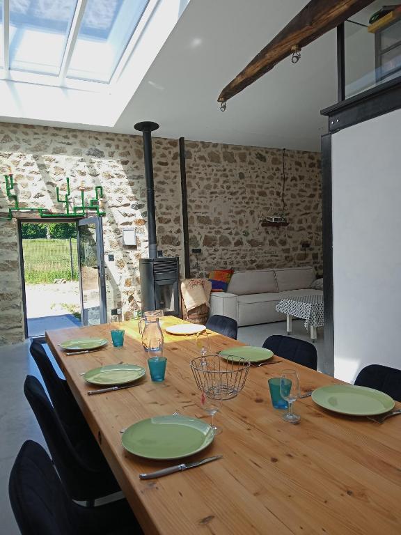 une table en bois avec des assiettes et des verres verts dans l'établissement Superbe grange rénovée, à Saint-Sulpice-le-Guérétois