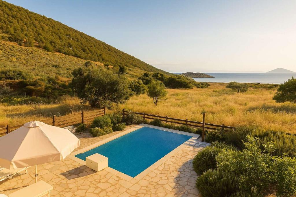 a swimming pool with an umbrella next to a hill at Seaside Aqua Bliss & Serenity with Private Pool in Koilás
