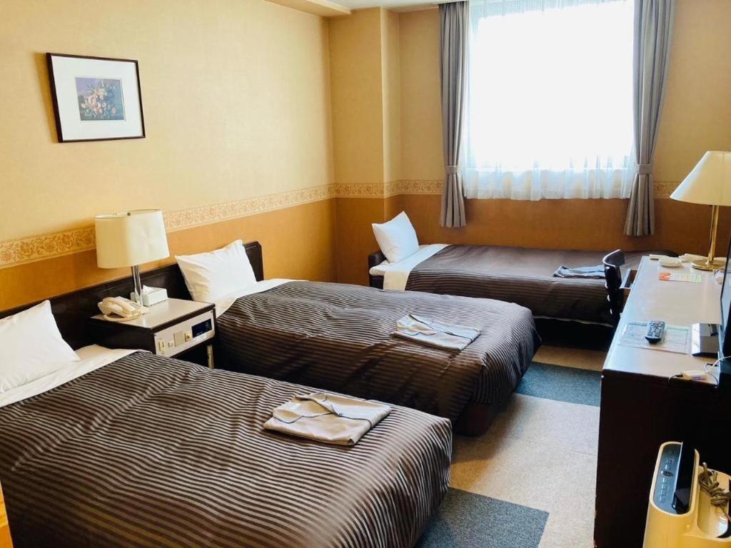 a hotel room with two beds and a window at The Hamilton Sapporo Hotel in Sapporo