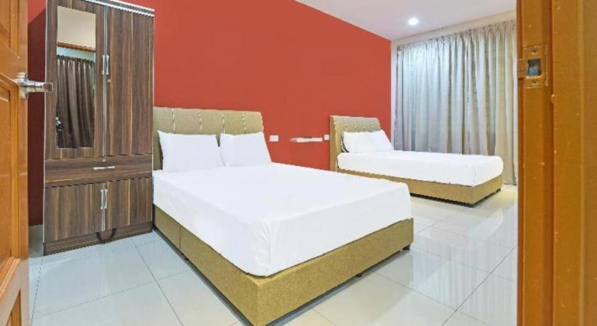 une chambre avec deux lits et un mur rouge dans l'établissement OYO 90522 Alma Sweet Home, à Juru